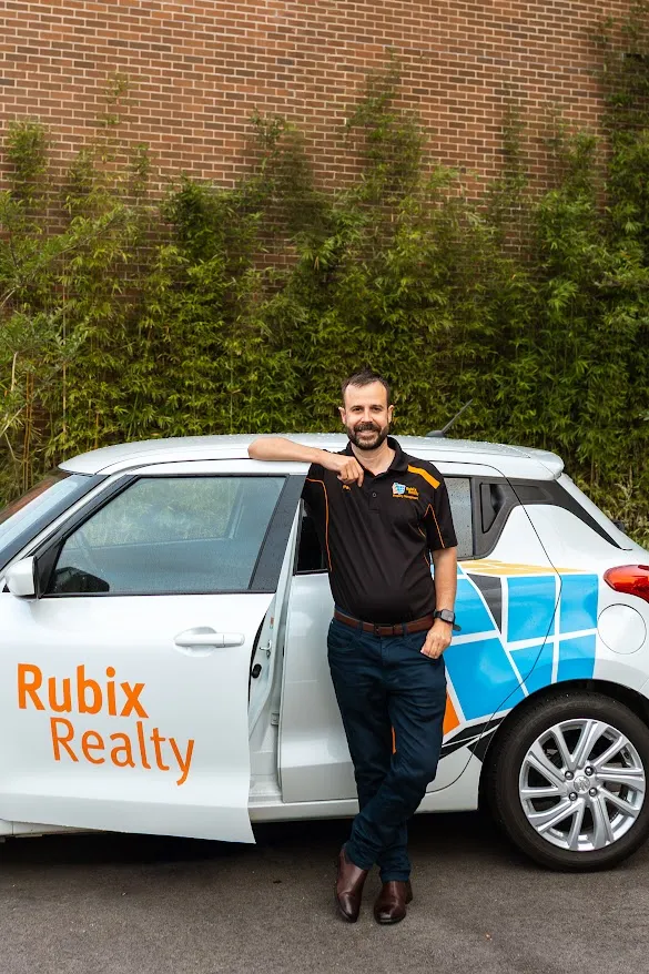 Pat Mears beside the Rubix Realty car, between inspections